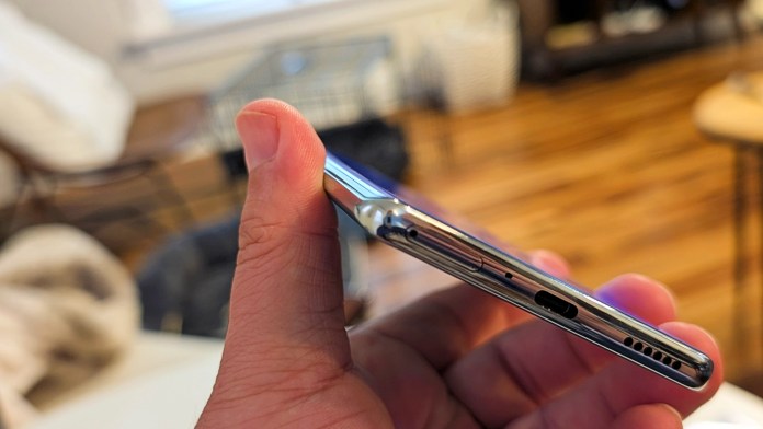 A close-up view of a hand holding the side of the TECNO Camon 40 Pro 5G smartphone, showcasing its slim profile, buttons, and port.