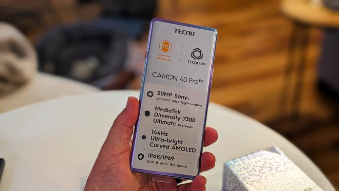 A person holding the TECNO Camon 40 Pro 5G smartphone showcasing its specifications and features such as a 50MP camera, MediaTek Dimensity 7300 processor, 144Hz AMOLED display, and IP68/IP69 dust and water resistance.