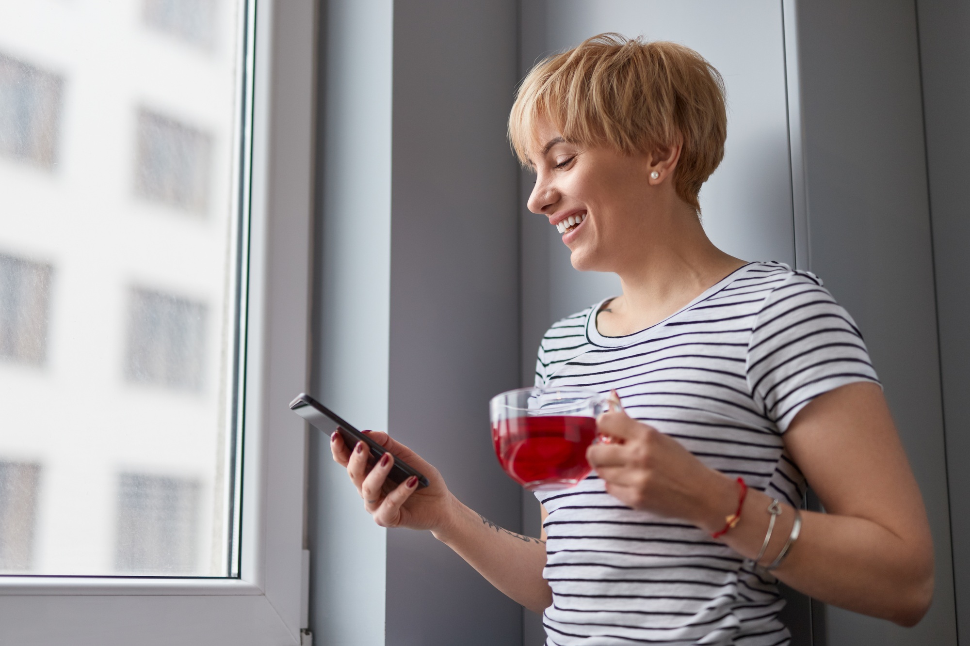 Cheerful female with tea shopping on phone