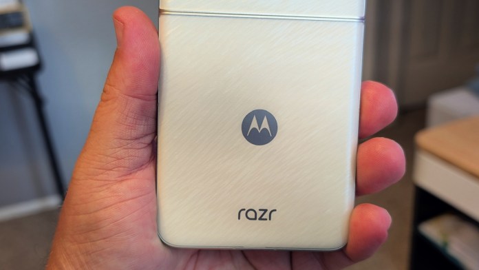 A person holding a Motorola Razr 2025 smartphone with a metallic finish, showcasing the Motorola logo and 'razr' branding on the back.