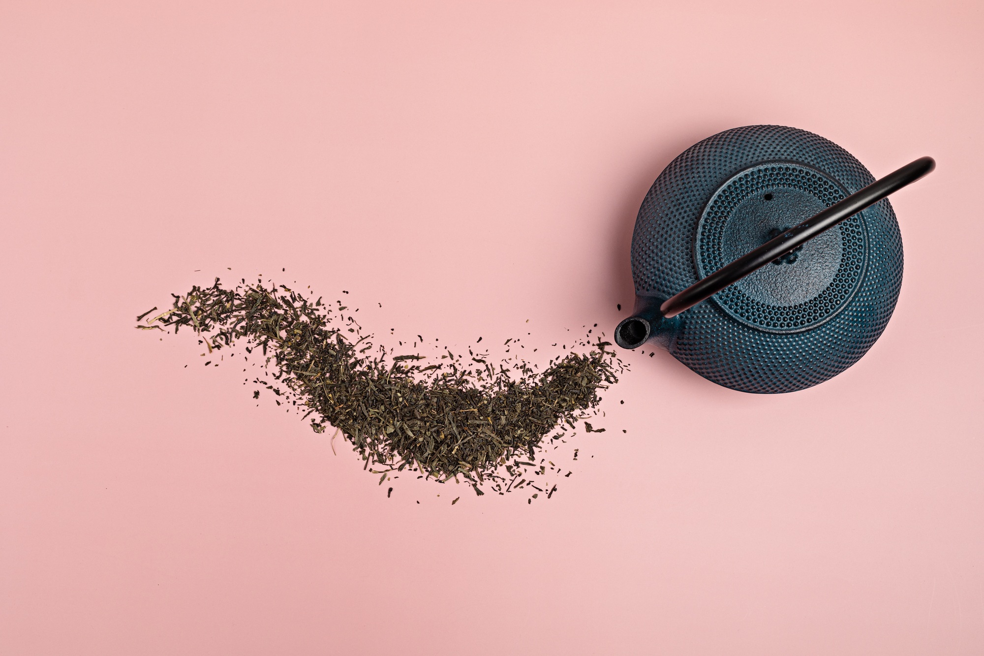 Tea pot with dry green tea leaves on pink background. Eco friendly organic brand concept. Branding