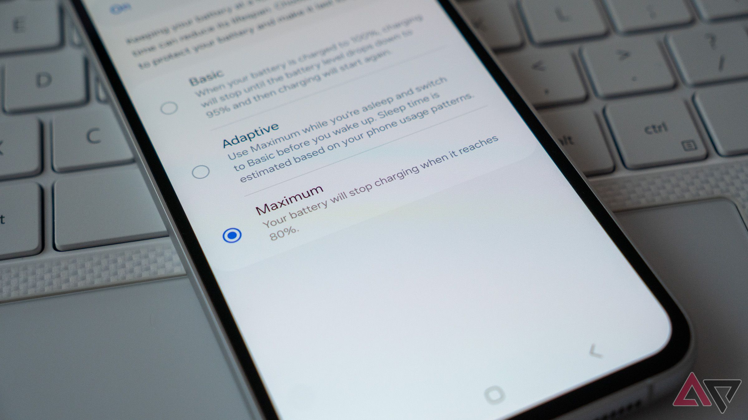 a phone on a laptop keyboard displaying the 80 percent charging limit setting