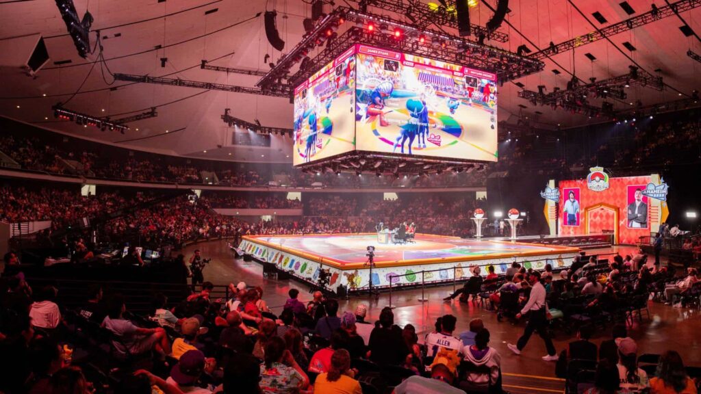Large crowd watching a Pokémon battle on big screen in championship arena