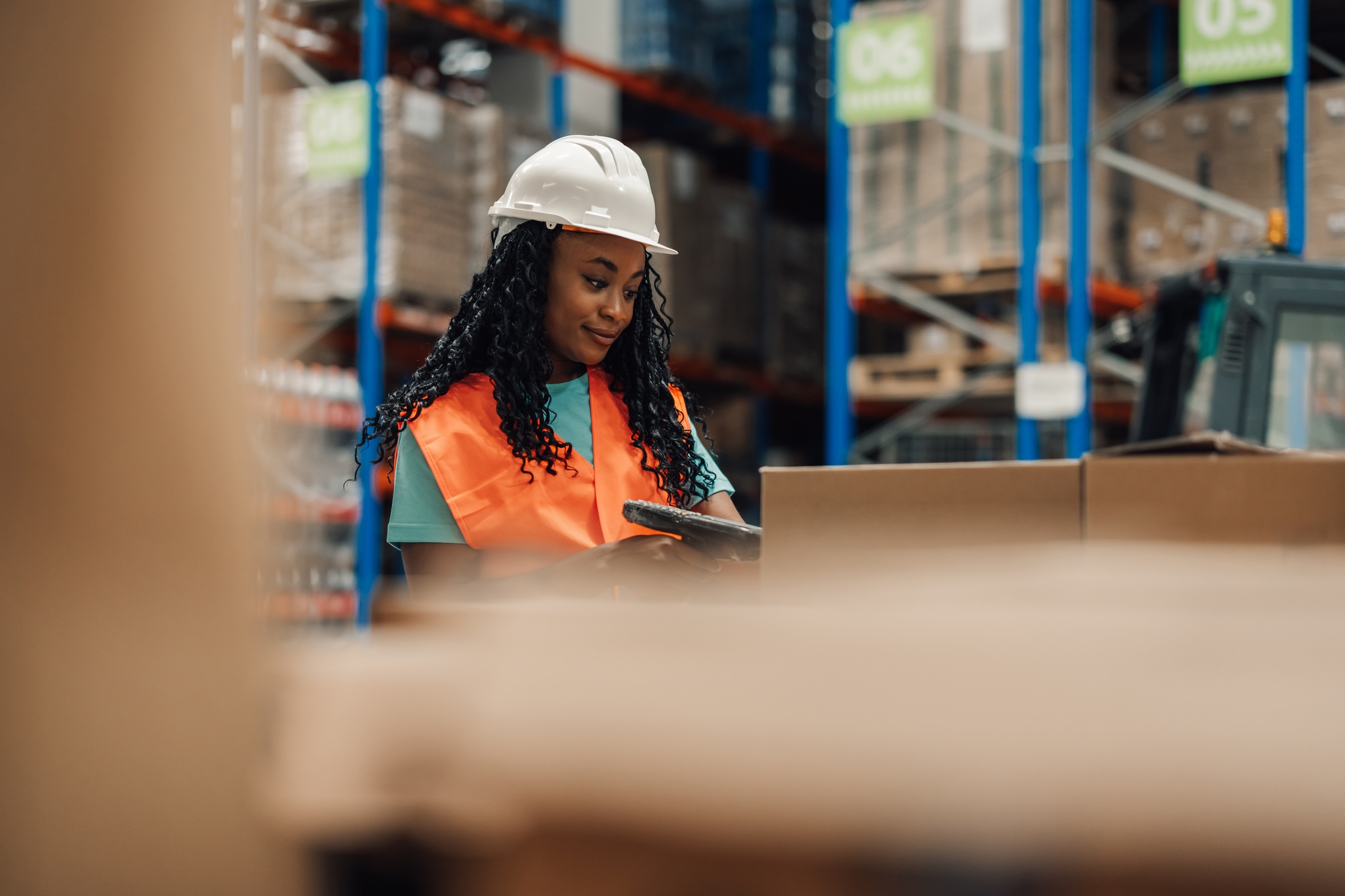 African american woman logging inventory in warehouse with boxes, hard-working.