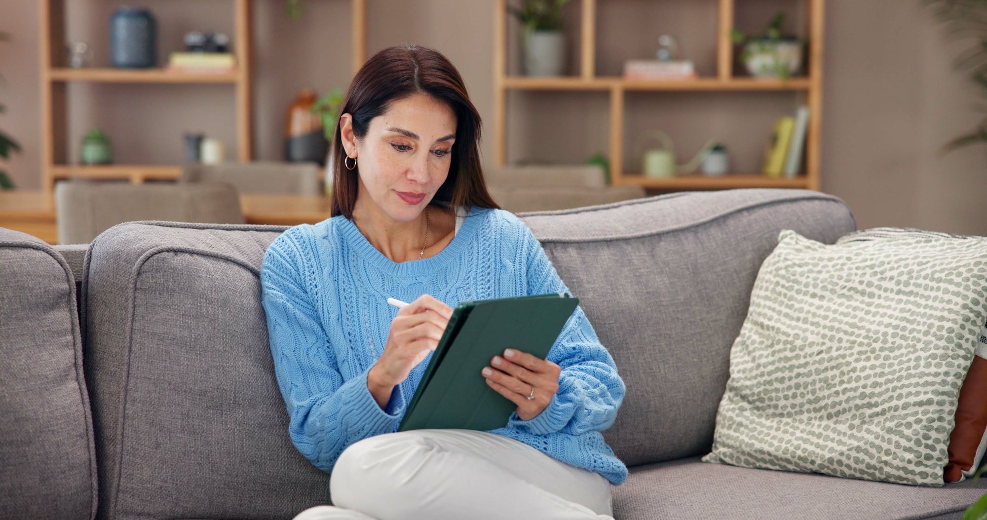 Woman, tablet and stylus on sofa in house with drawing startup brand logo, remote work and design i